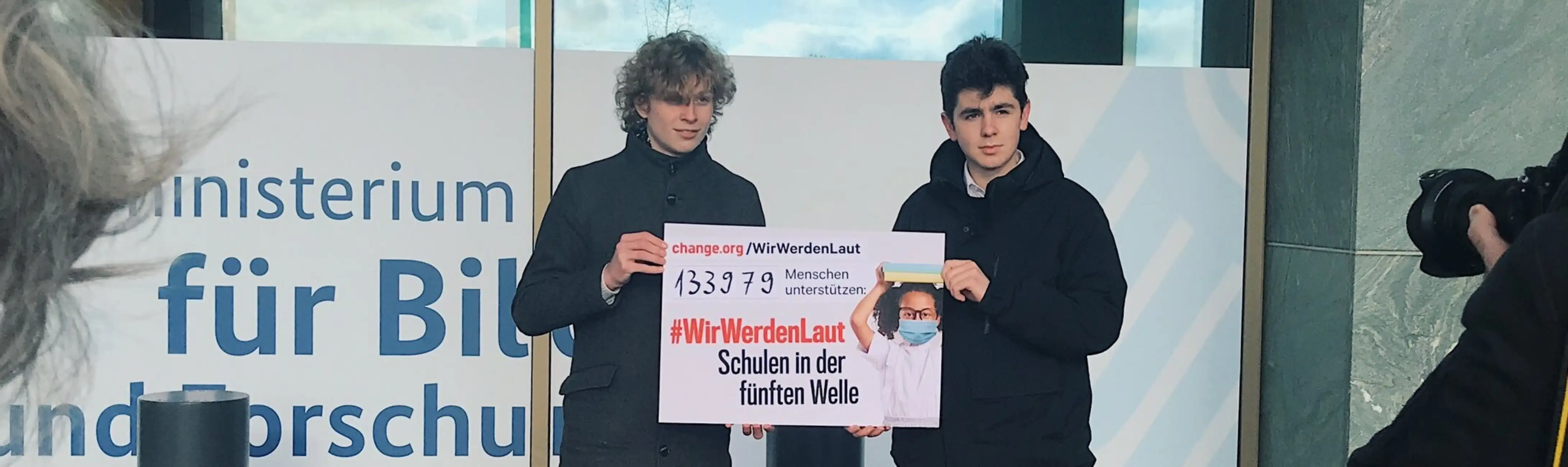 Anjo Genow und Tobias Westphal halten ein Plakat mit der Anzahl der Unterschriften hoch